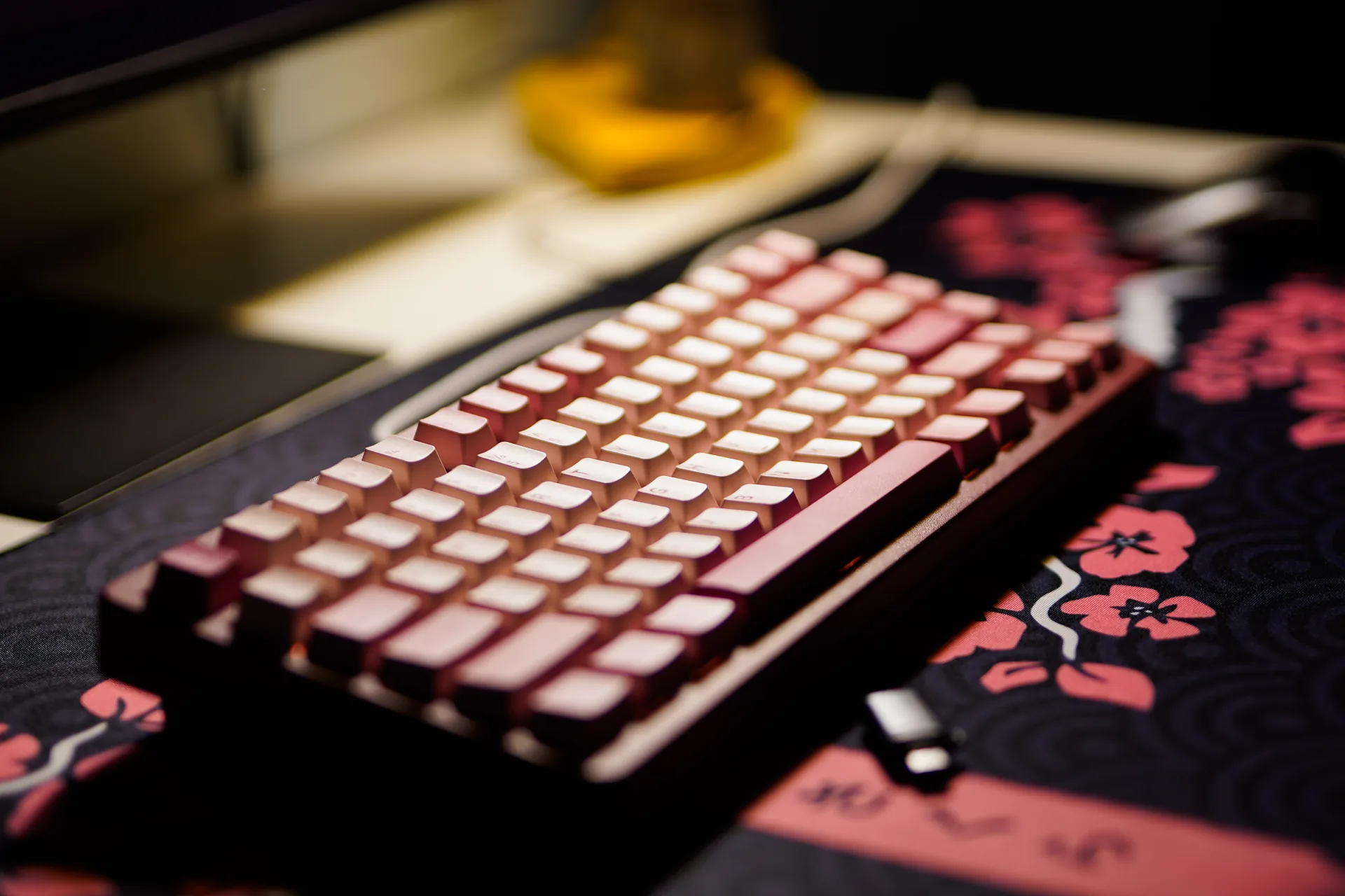 A pink mechanical keyboard on a floral desk mat