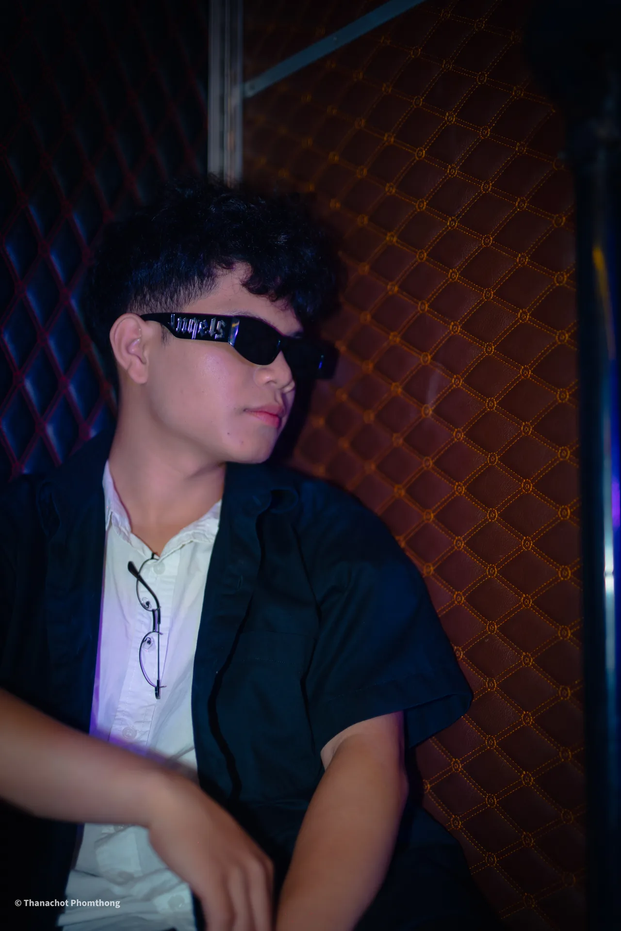 Thanachot Phomthong wearing sunglasses in a dimly lit room